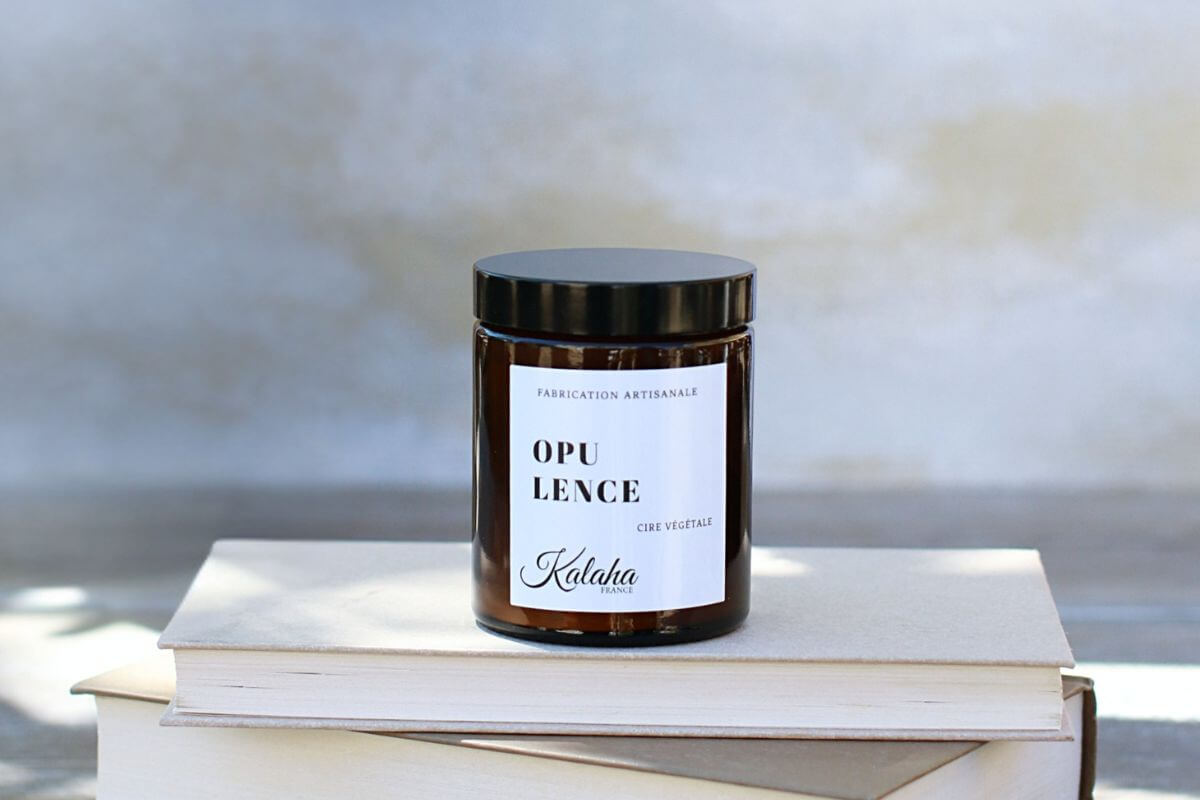Bougie parfumée Opulence de Kalaha en verre ambré sur des livres